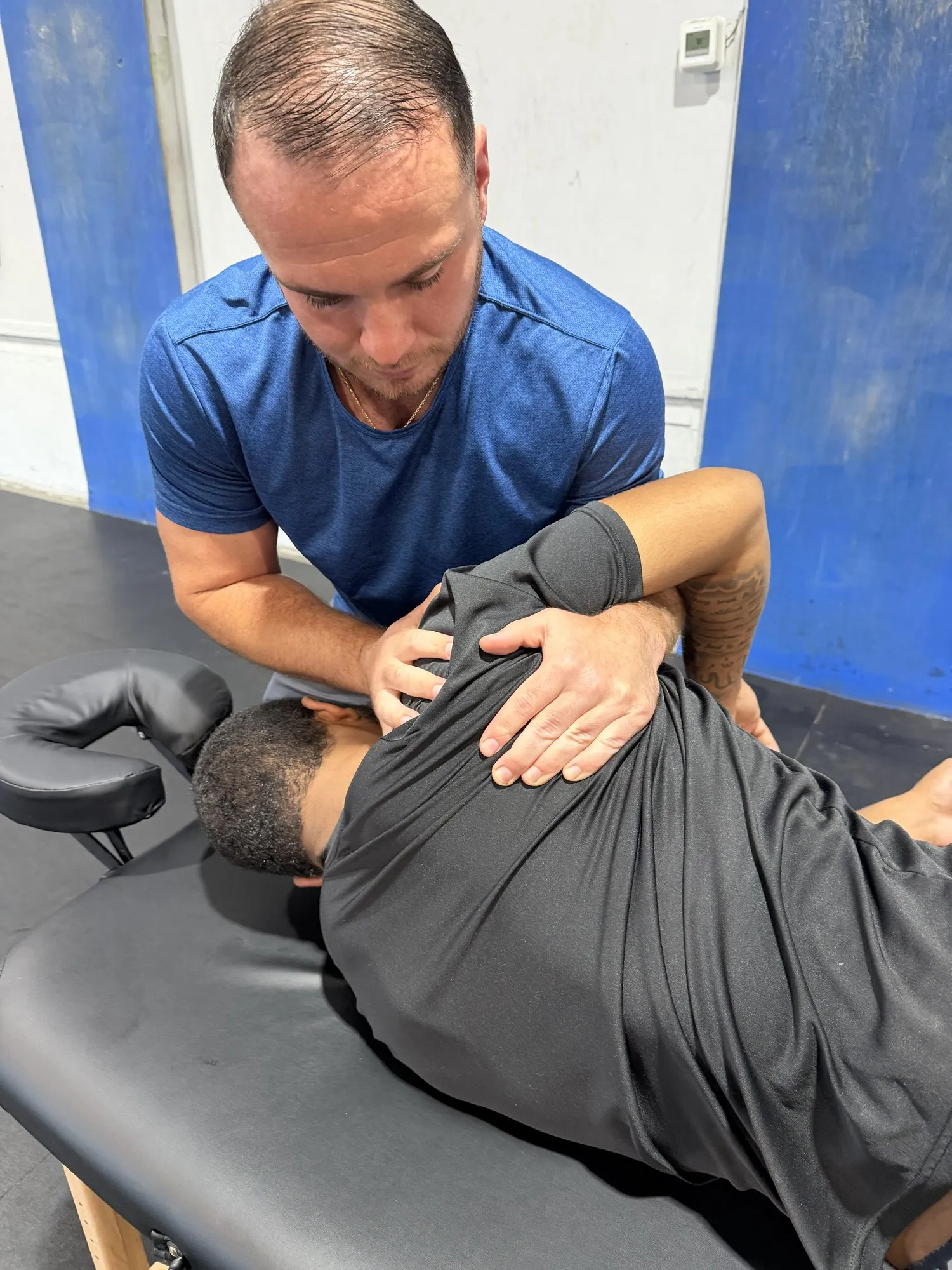 Kyle doing hands-on shoulder work with a client lying on a treatment table