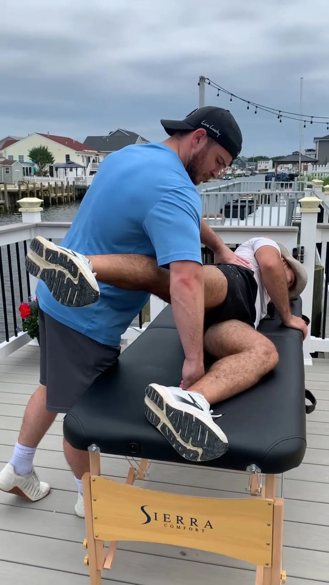 Kyle stretching a client's hip on a portable treatment table outdoors